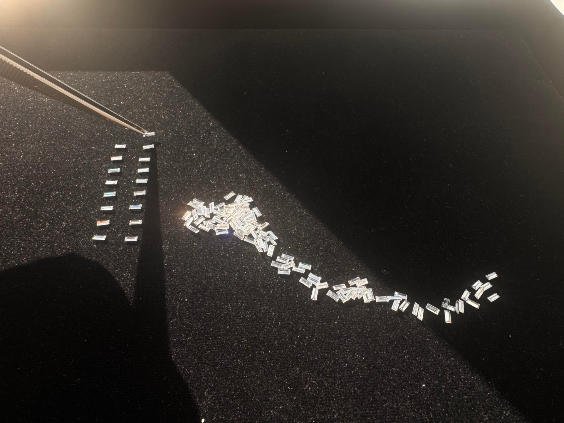 Calibrated baguette diamonds assorted and aligned on a dark tray